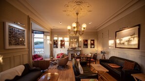 Un salon spacieux doté d’une cheminée, de sièges confortables et d’un lustre.