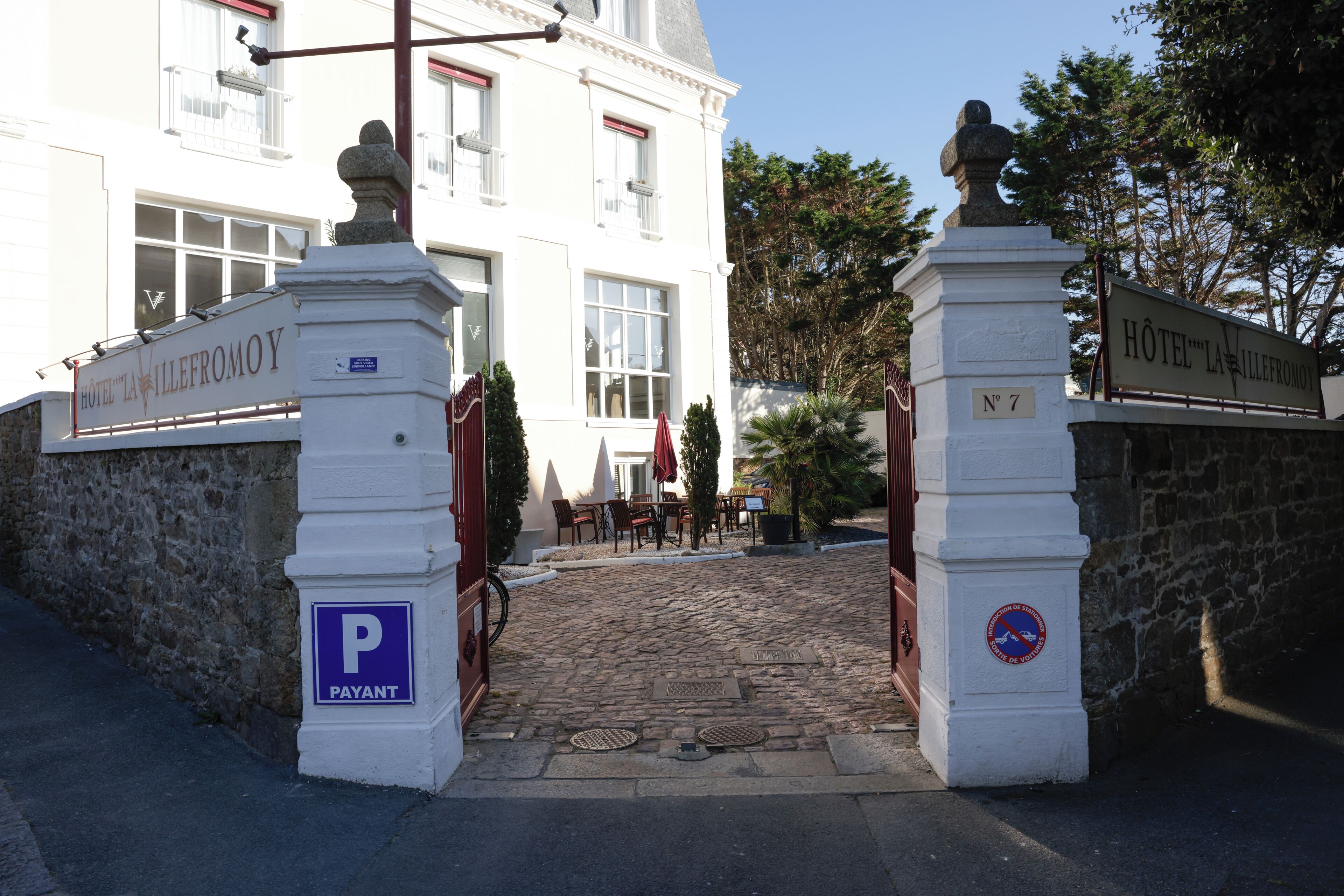 Una entrada de hotel con un camino adoquinado que lleva a un acceso con puerta.