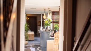 Un espace d’accueil comprenant un comptoir, une plante et un coin salon avec des chaises.