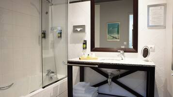 Une salle de bain moderne avec une douche à parois de verre, un meuble-lavabo avec un évier et un miroir, et des serviettes soigneusement pliées.