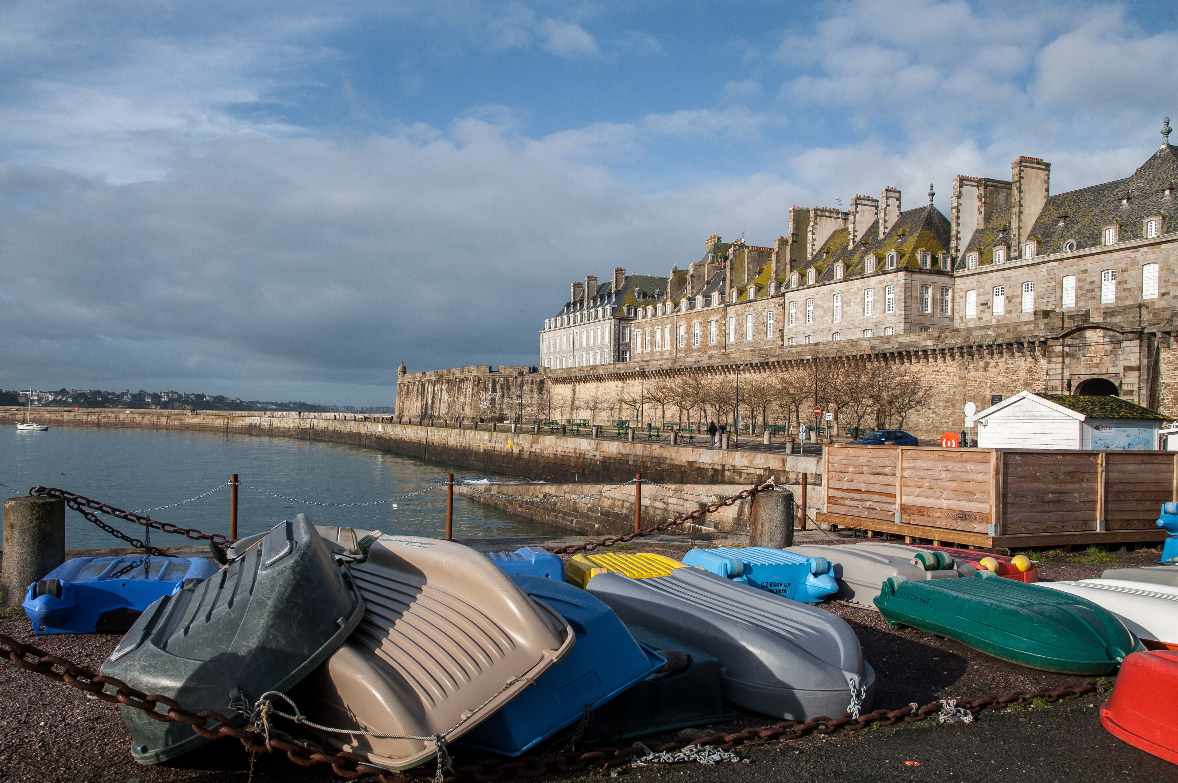 A waterfront with boats docked and a historic building in the background.
