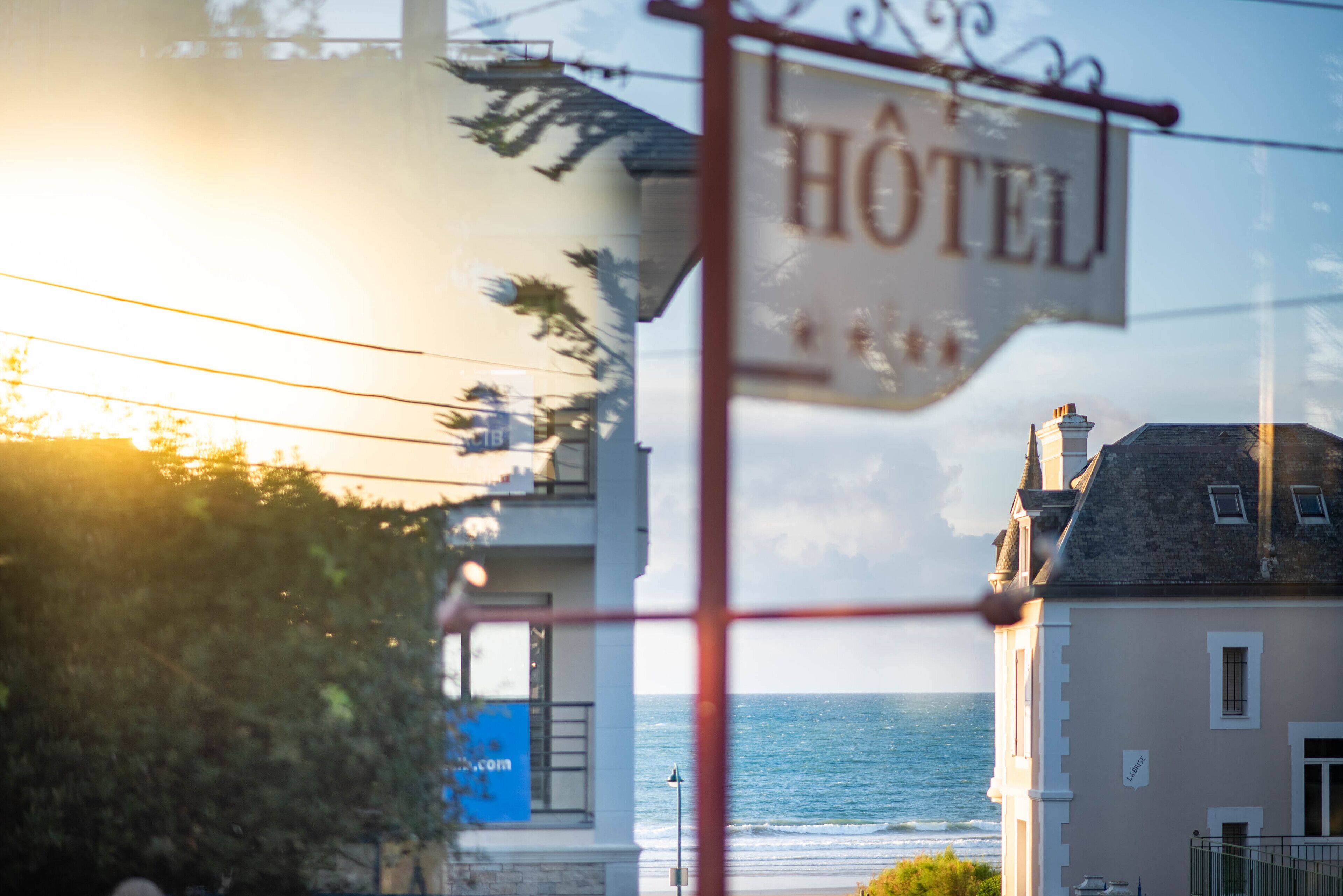 A hotel sign with the word "Hôtel" and a view of the sea.