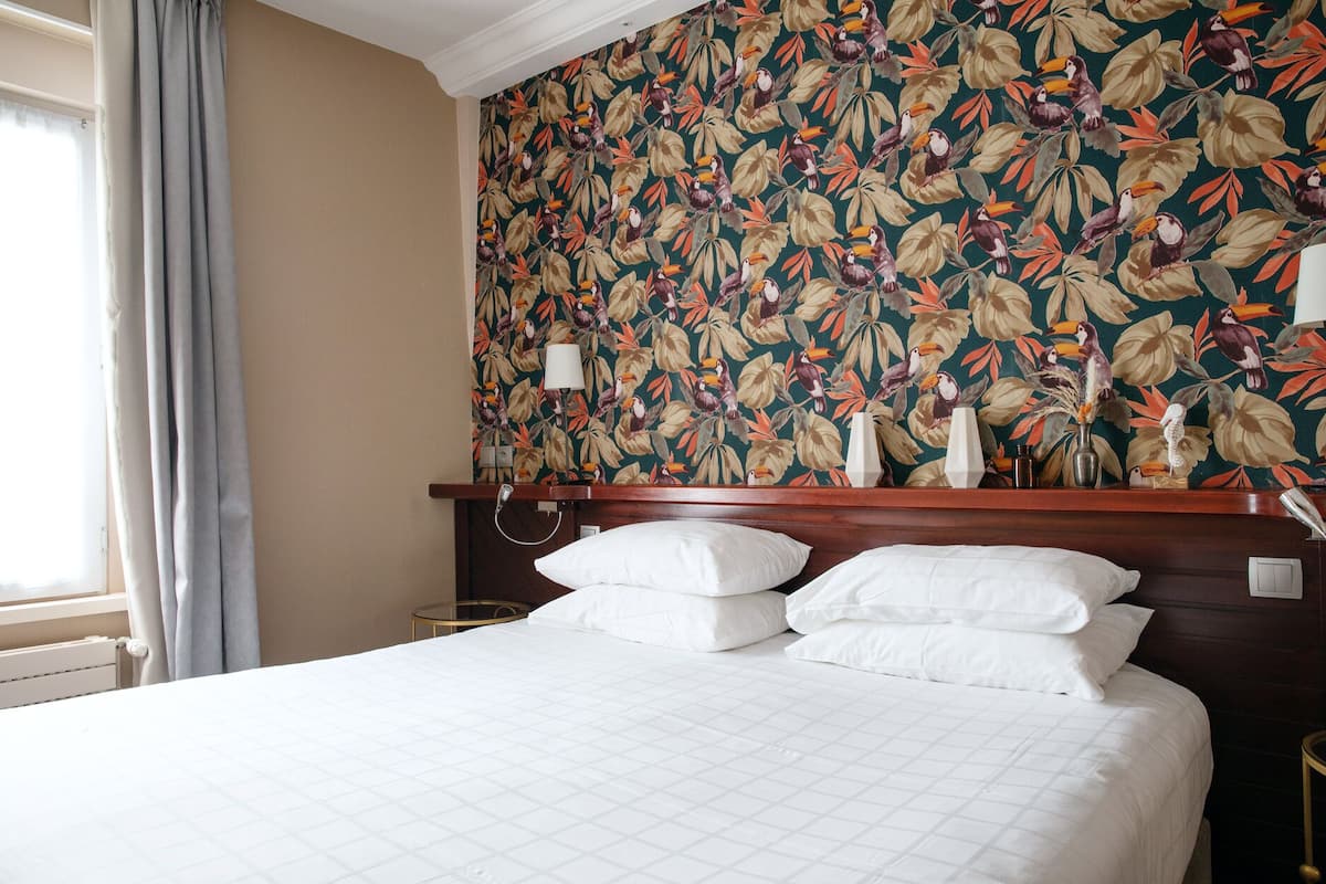 Een hotelkamer met een groot bed, een houten hoofdbord en bloemenbehang.