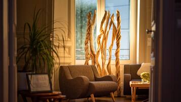 A living room with a sofa, a table with a vase, and a plant.