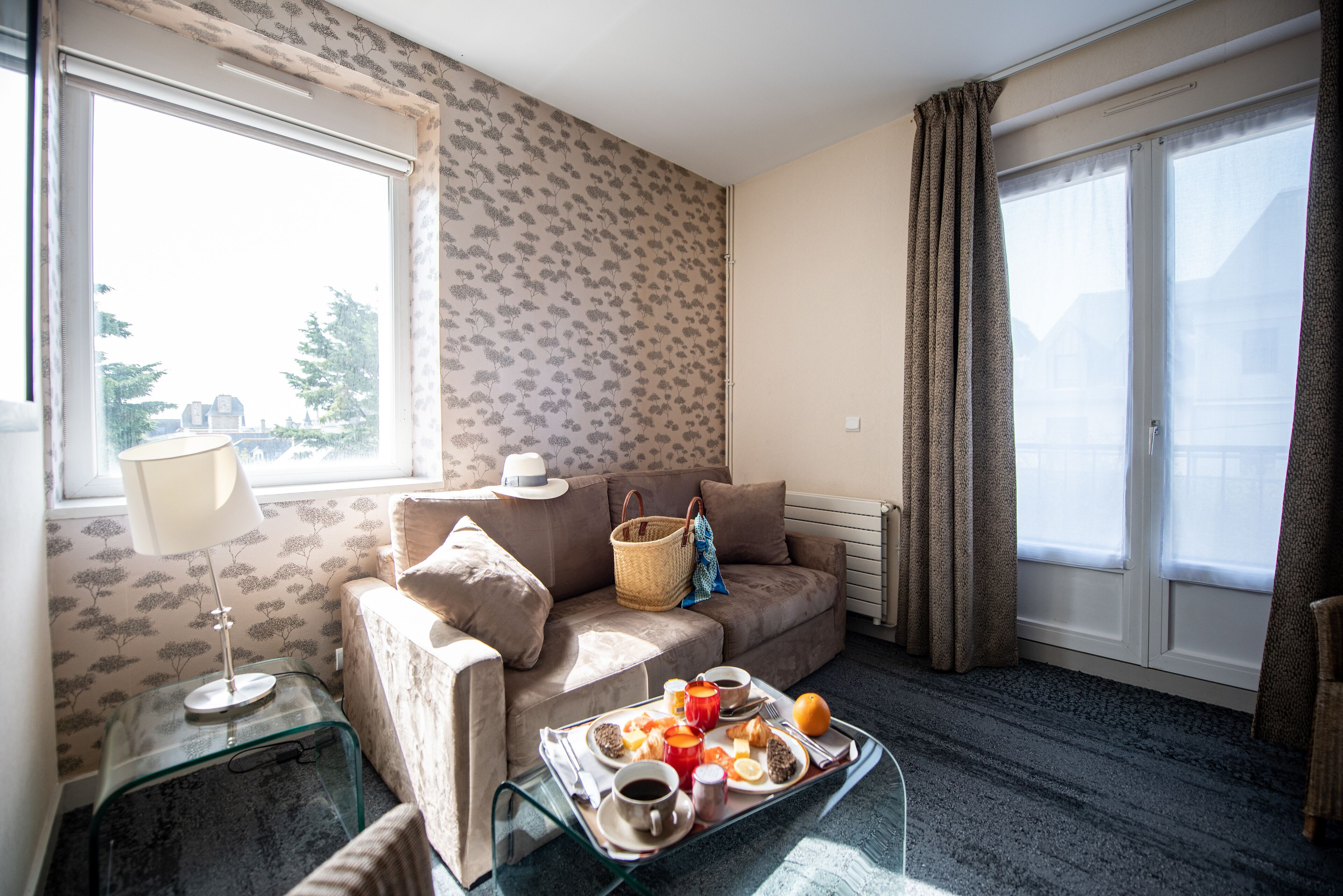 Ein gemütliches Zimmer mit Sofa, Frühstücksbrett und einem Vorhangfenster.