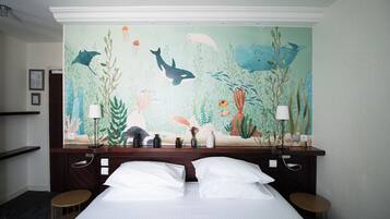 Habitación de hotel con una cama, dos mesitas de noche y un mural con motivos marinos en la pared.