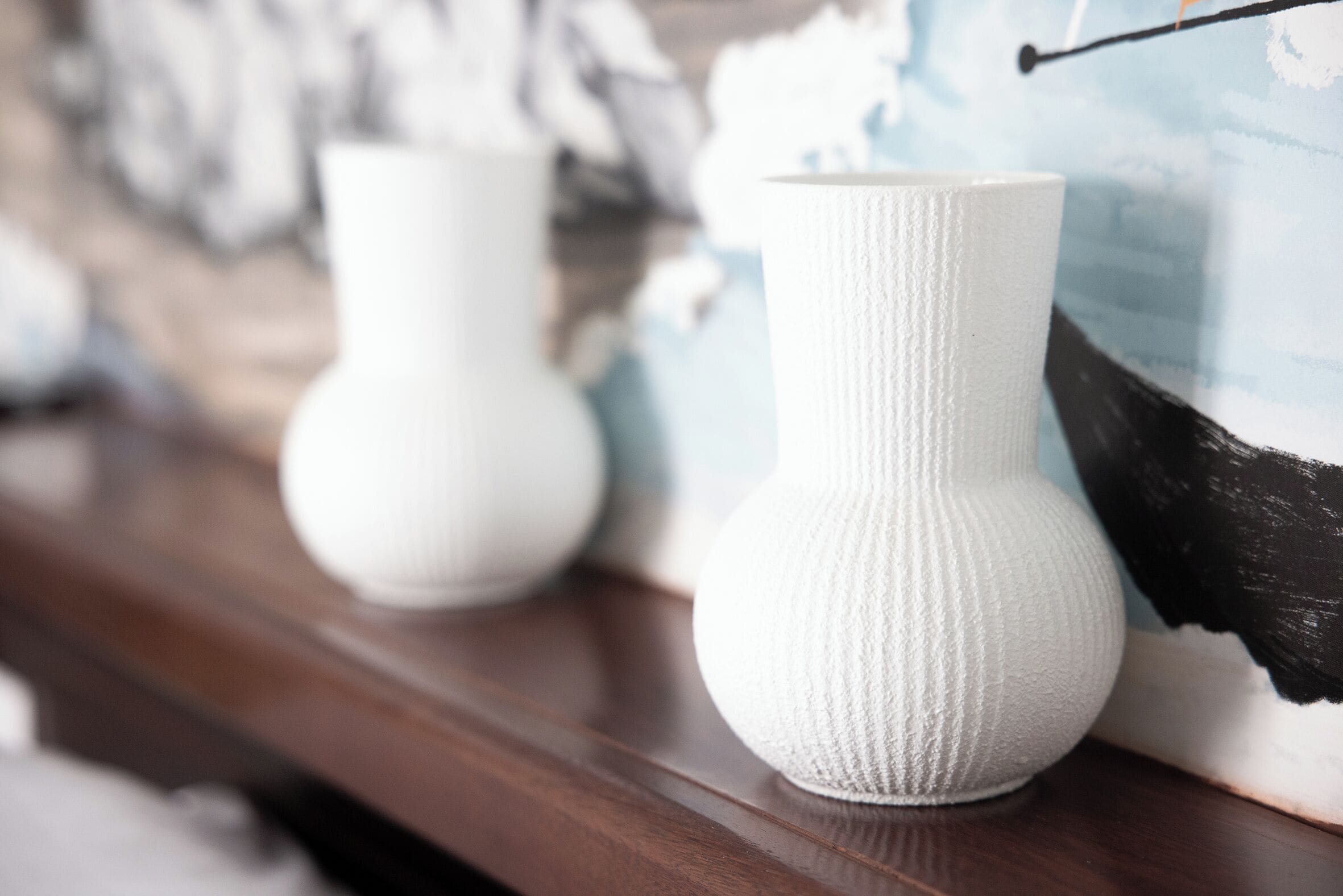 Two white vases on a wooden surface.
