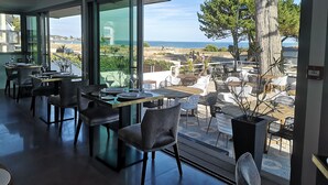 A modern dining area with large windows overlooking a scenic coastal view. - Le Diana Hotel and Spa (Carnac)