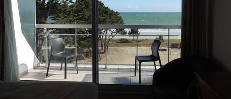 A room with a balcony overlooking a beach and ocean.