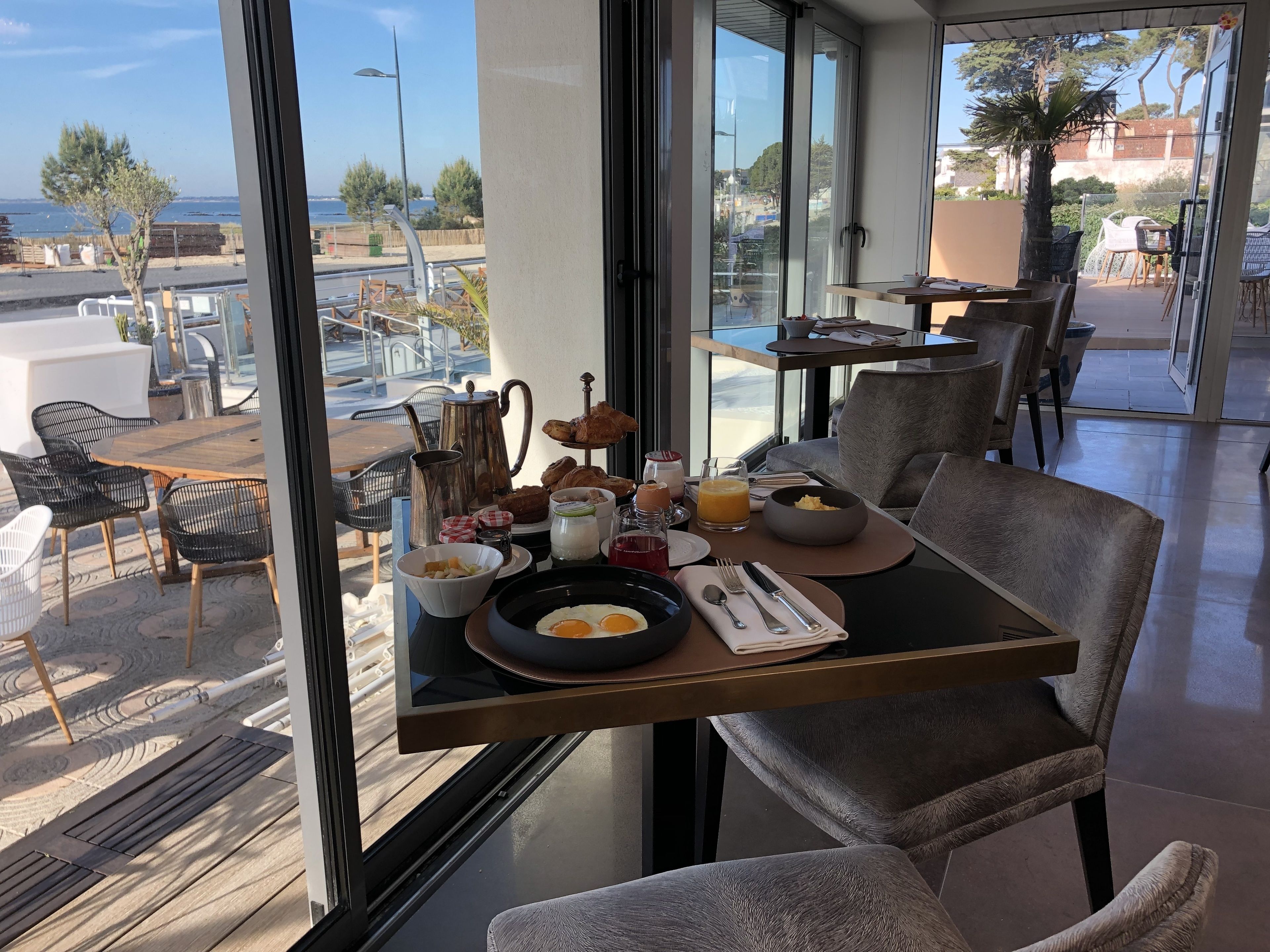 Una mesa de desayuno con diferentes alimentos y vista al mar.