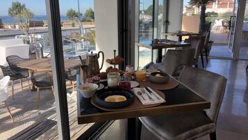 Una mesa de desayuno con diferentes alimentos y vista al mar.