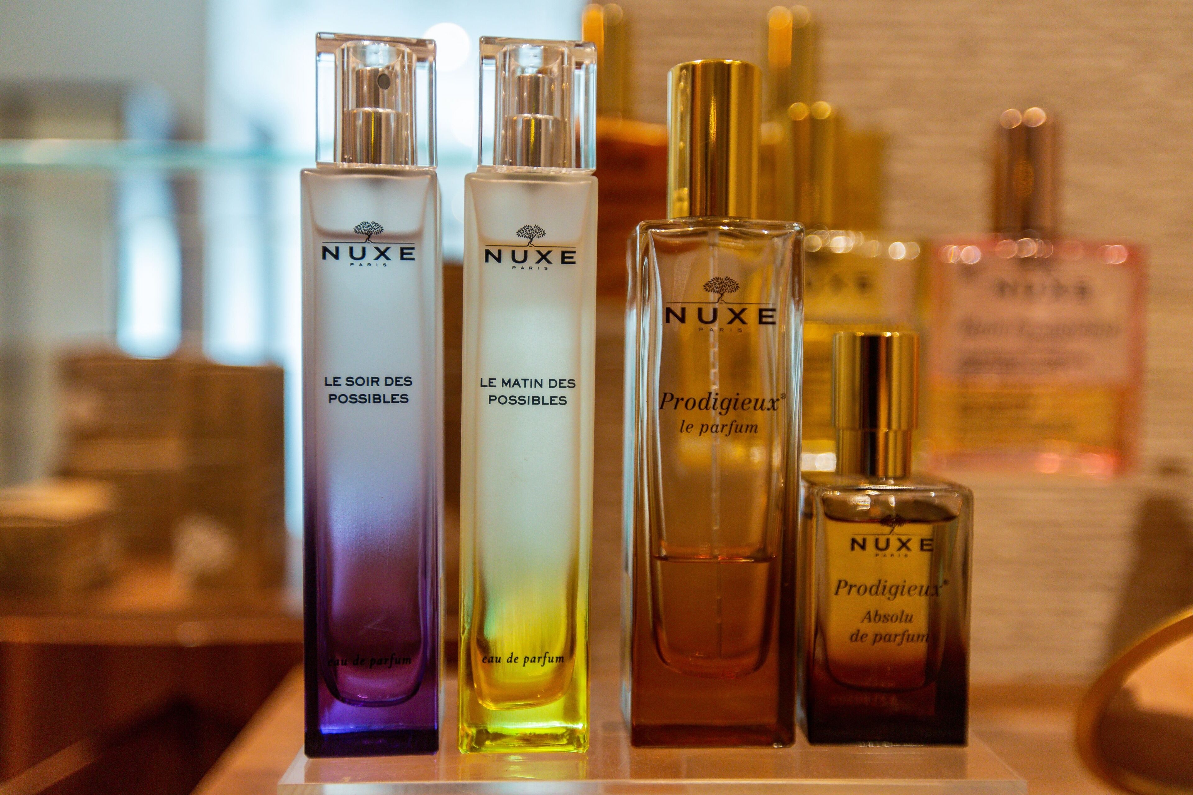 Une présentation de flacons de parfum Nuxe dans différentes couleurs.