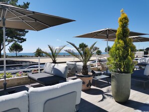 A rooftop terrace with outdoor seating, umbrellas, and potted plants.