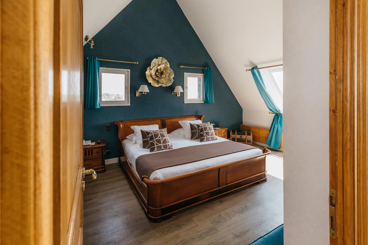 Ein Schlafzimmer mit einem großen Bett, einem Holz-Kopfende, zwei Nachttischen und einem Fenster mit Vorhängen.