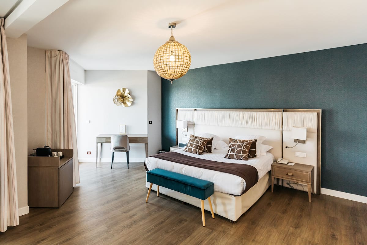 Ein modernes Schlafzimmer mit einem großen Bett, Nachttischen, einem Schreibtisch und einer Hängeleuchte.