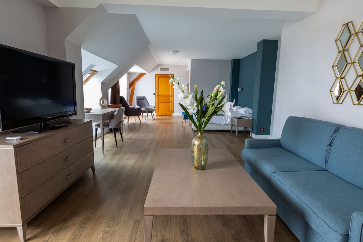 Ein modernes Wohnzimmer mit Flachbildfernseher, einer Couch, einem Couchtisch und einer Blumenvase.