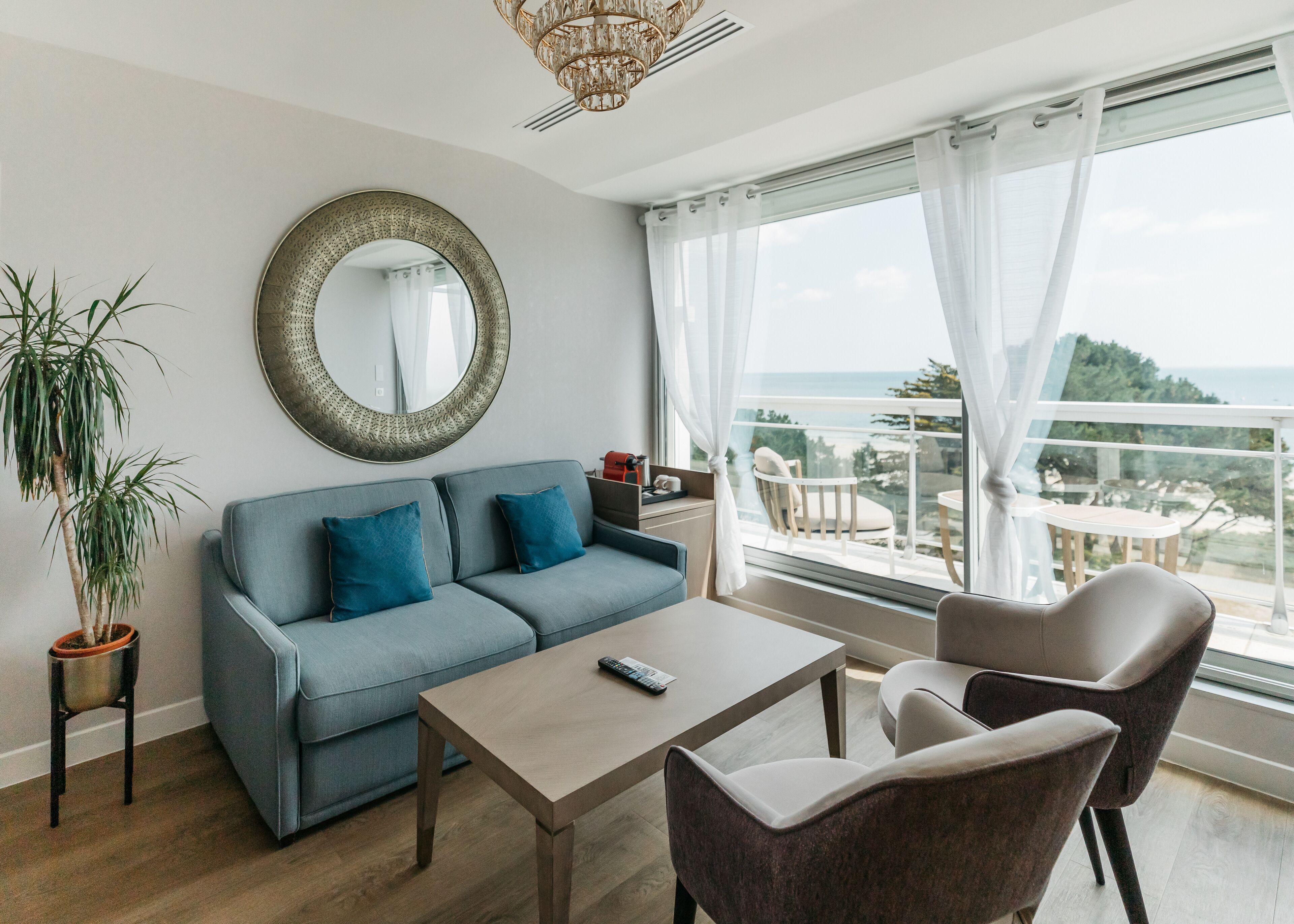 A modern living room with a sofa, a coffee table, and a view of the ocean.