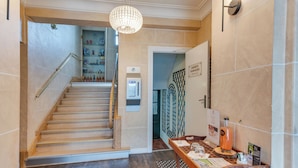 A hotel lobby with a staircase, a reception desk, and a water dispenser. - BRIT HOTEL CONFORT CLERIA LORIENT Centre (Lorient)