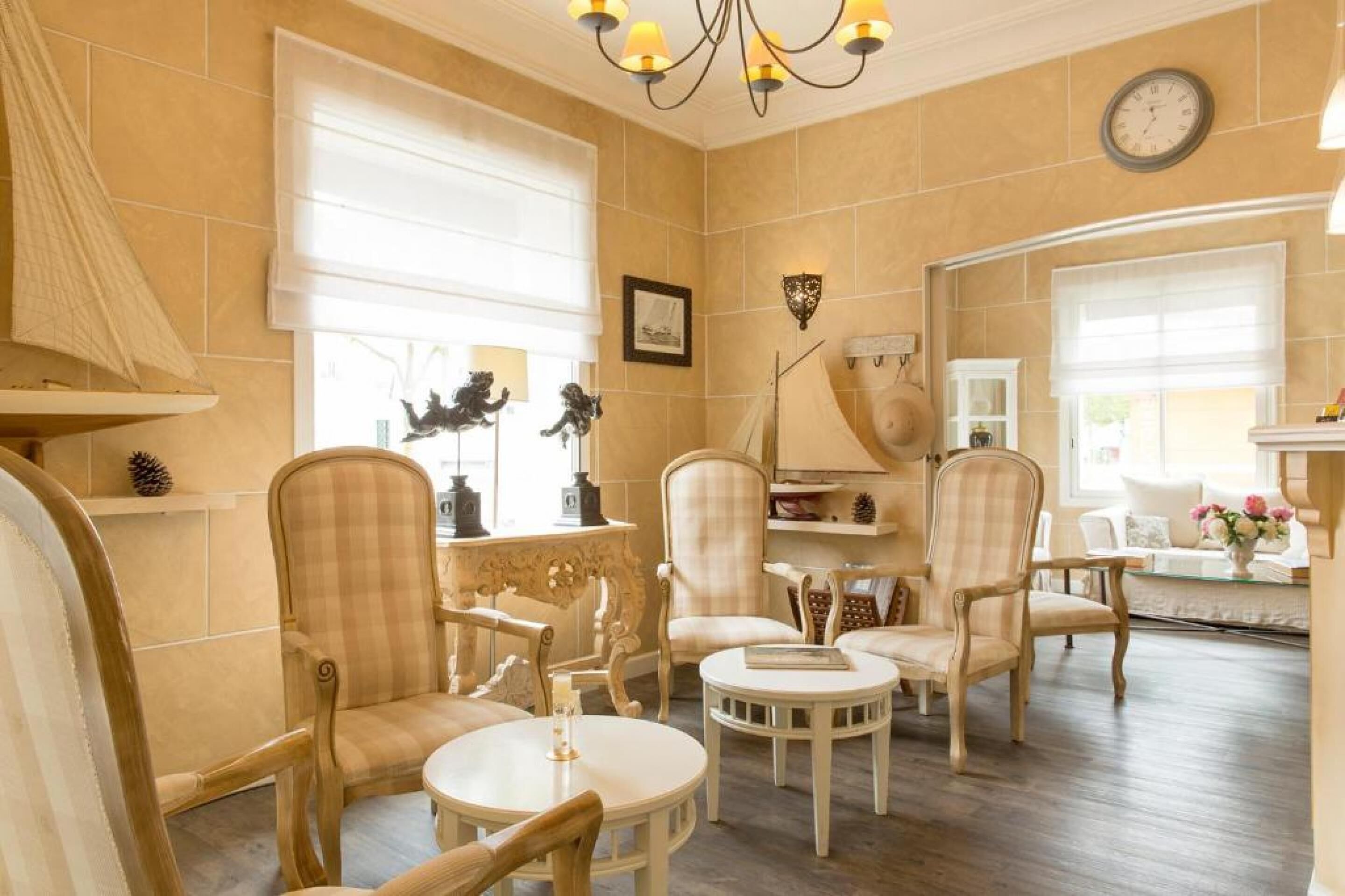 A room with a fireplace, two armchairs, a round table, and a clock on the wall.
