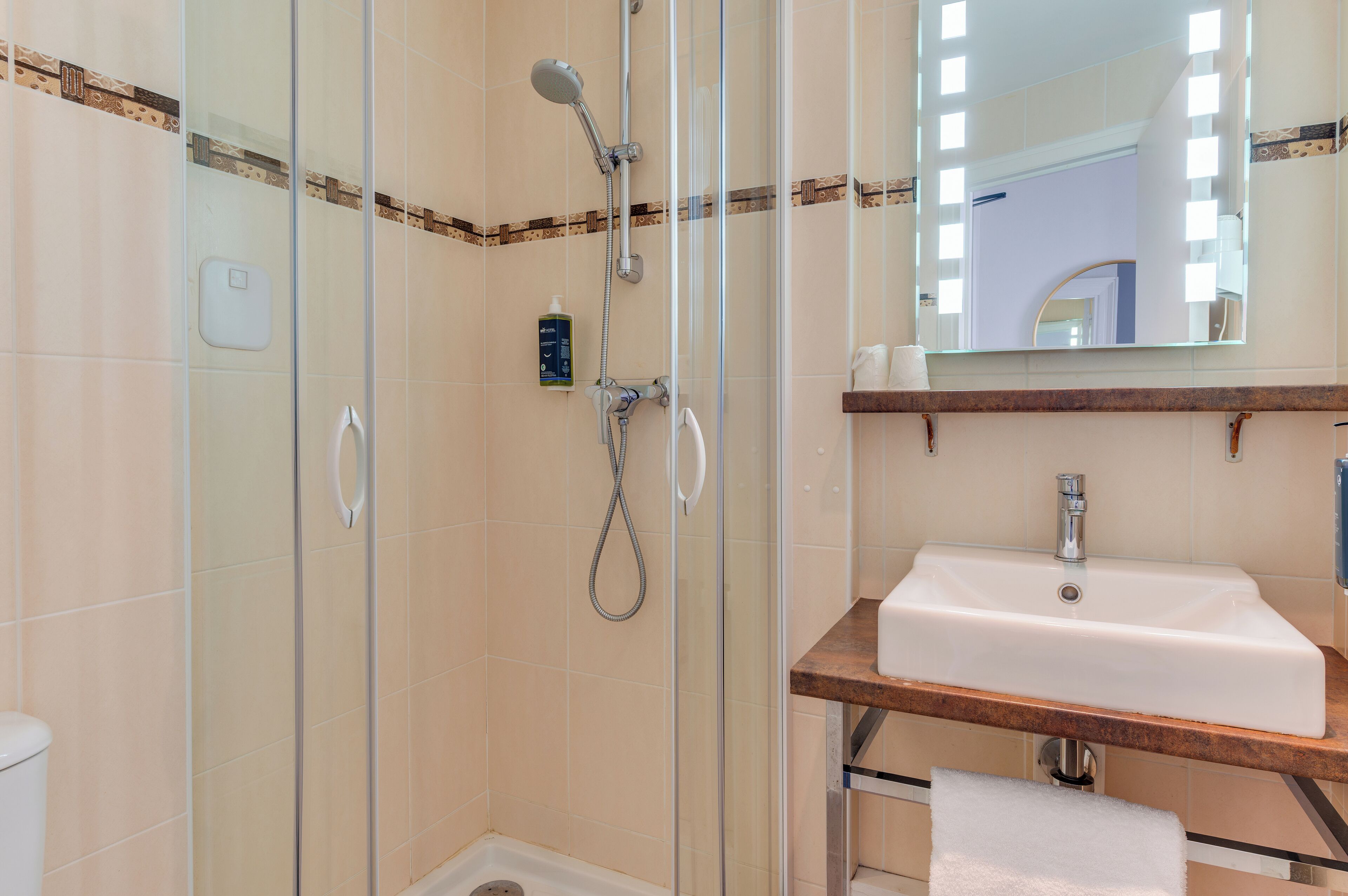 Une salle de bain avec une douche à parois de verre, un lavabo blanc et un miroir au-dessus du lavabo.