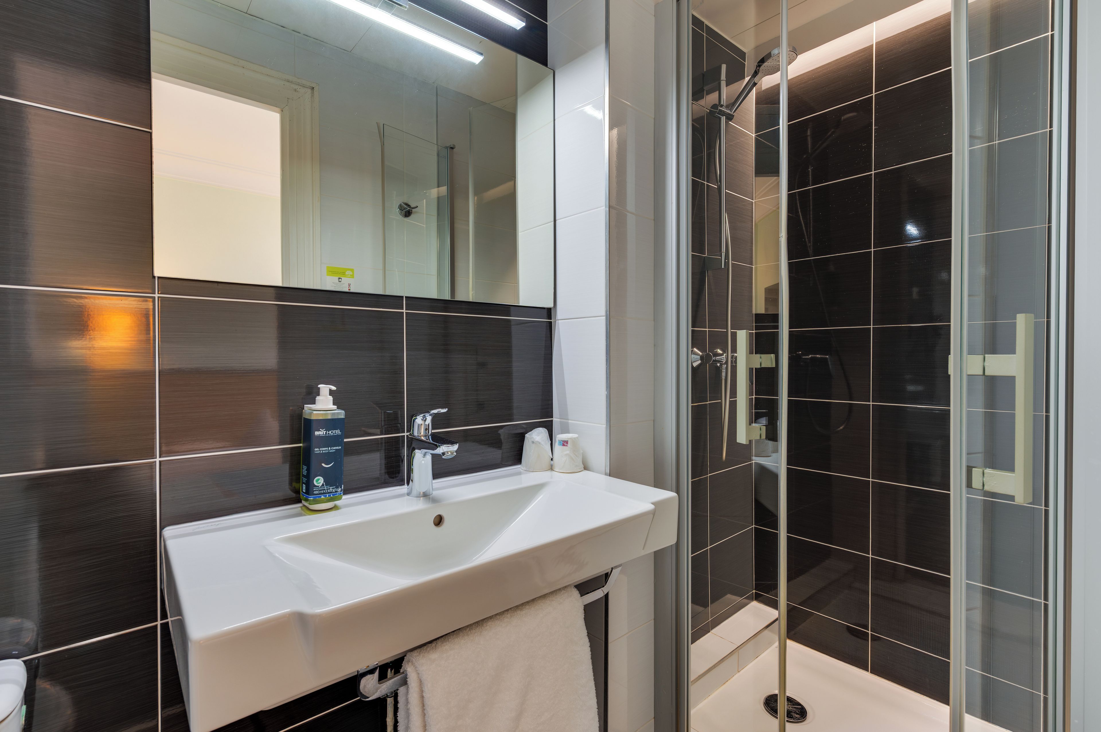Un baño moderno con un lavamanos blanco, un espejo y una cabina de ducha de vidrio.