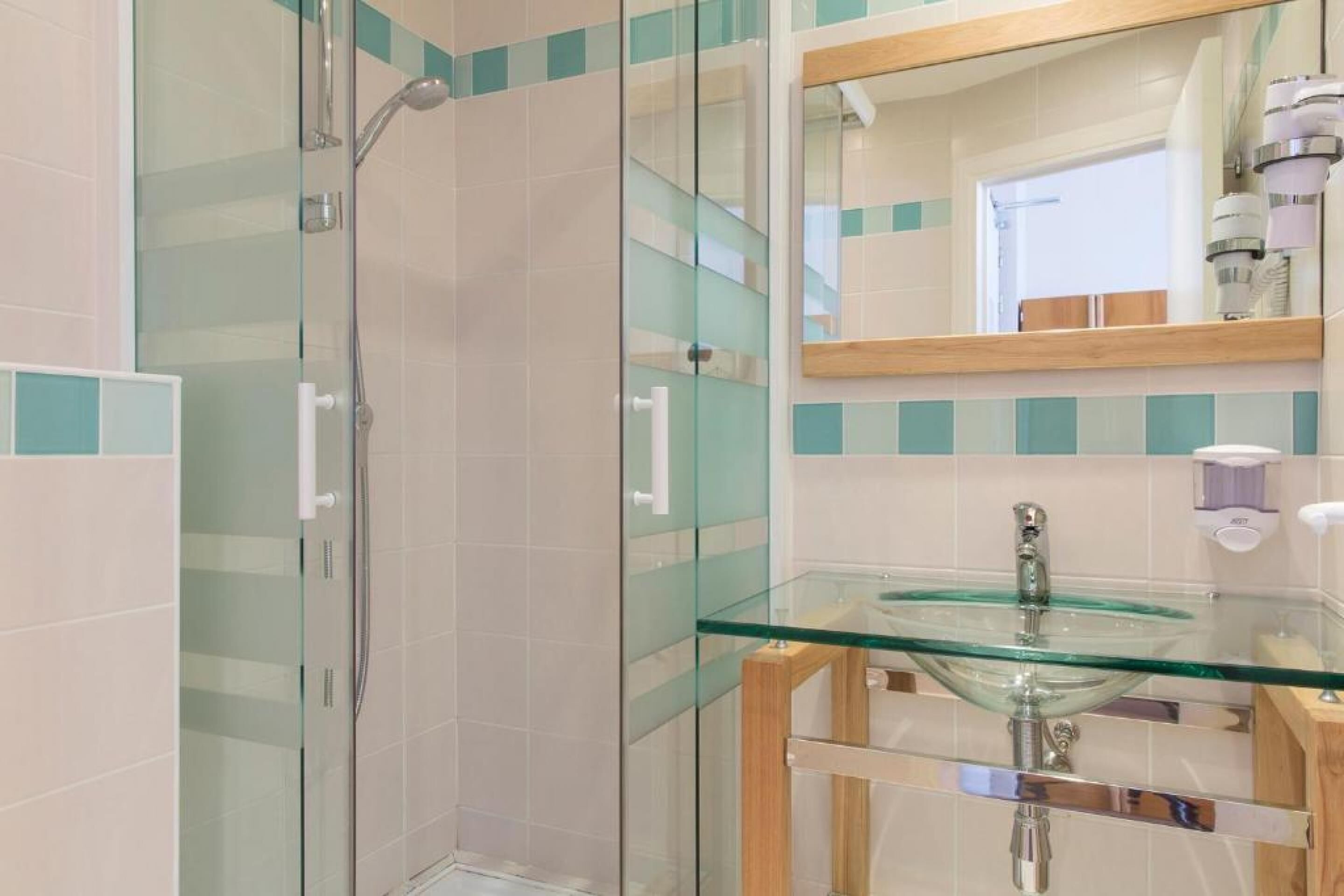 A bathroom with a glass shower enclosure, a glass sink, and a mirror.