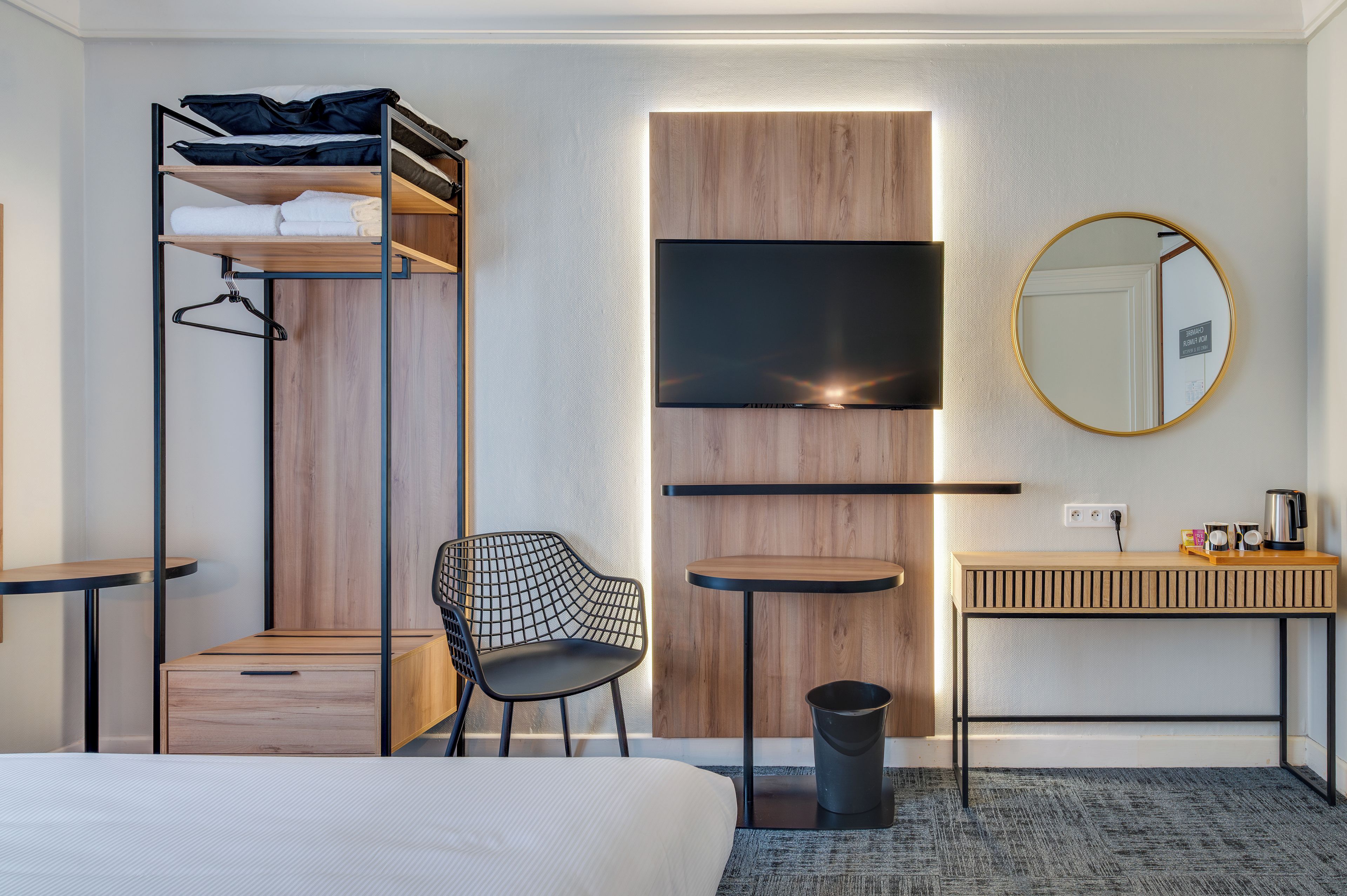 Habitación de hotel con literas, un escritorio, una silla, un espejo y un televisor.