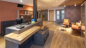 A reception area with a desk, computer, and seating area with chairs and a sofa. - Sure Hotel by Best Western Dole (Dole)
