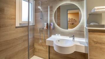 Un baño moderno con pared de madera, espejo redondo, lavamanos y ducha.
