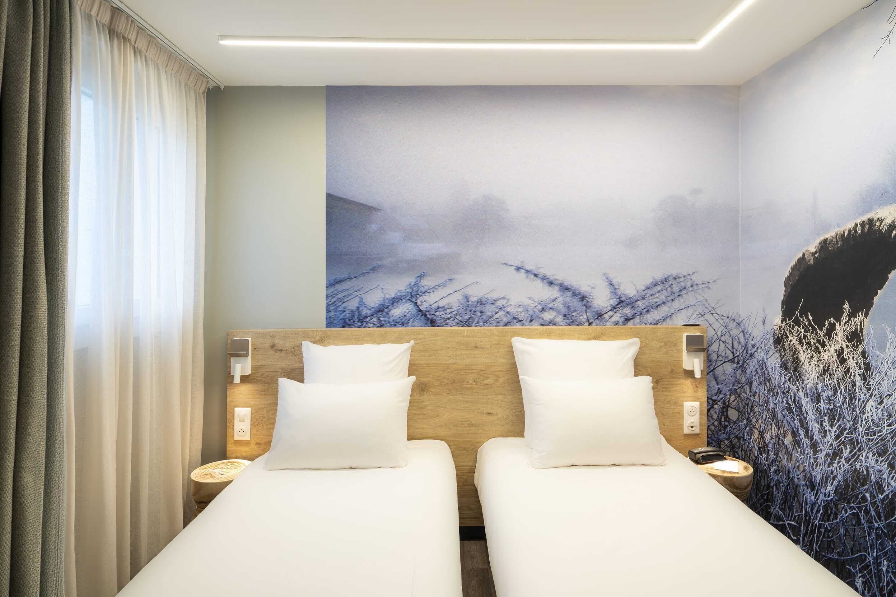 Een hotelkamer met twee bedden, een houten hoofdbord, een nachtkastje en een wanddecoratie.