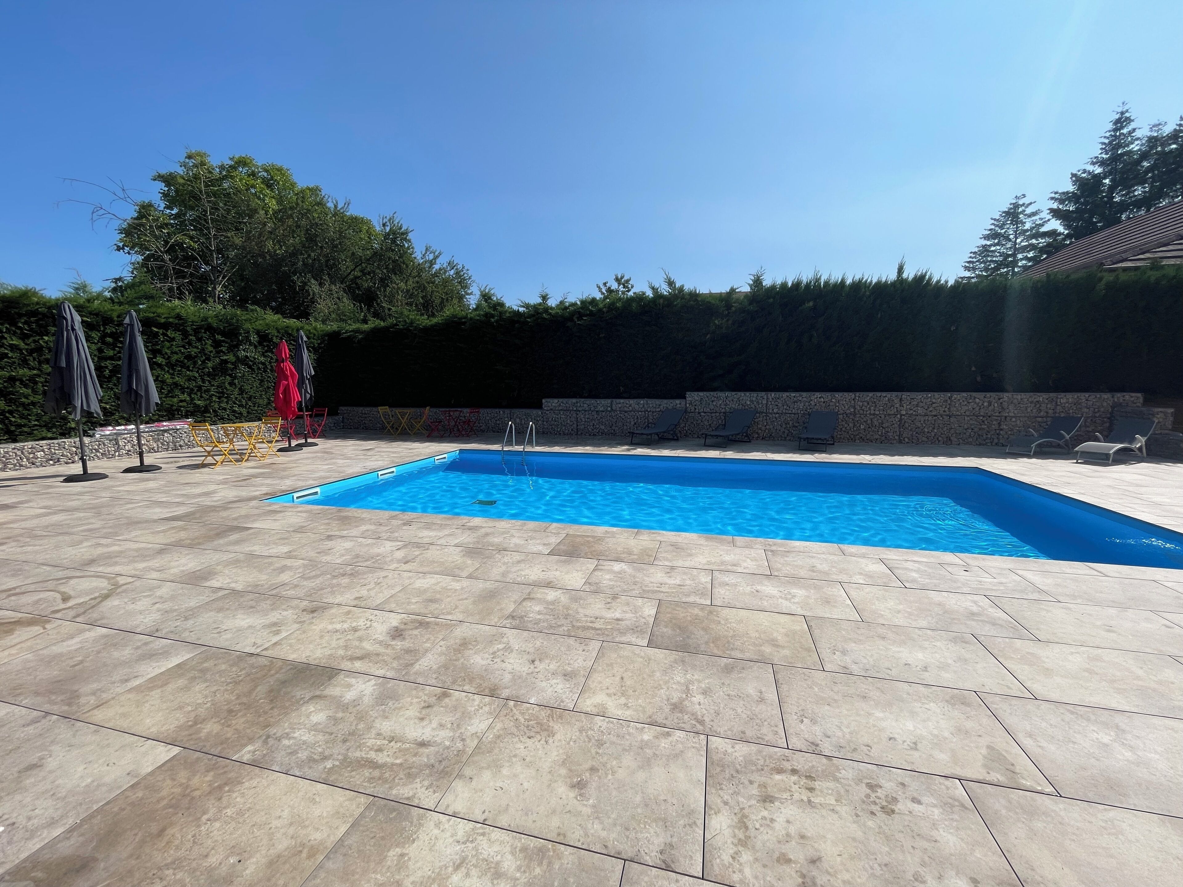 Une piscine rectangulaire à l’eau d’un bleu limpide, entourée d’une terrasse carrelée.