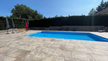 Une piscine rectangulaire à l’eau d’un bleu limpide, entourée d’une terrasse carrelée.