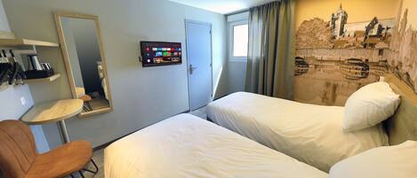 A hotel room with two beds, a desk with a chair, a mirror, a TV, and a mural on the wall.