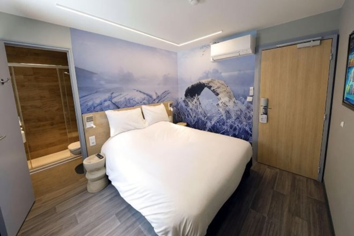 A bedroom with a bed, a shower, and a door.