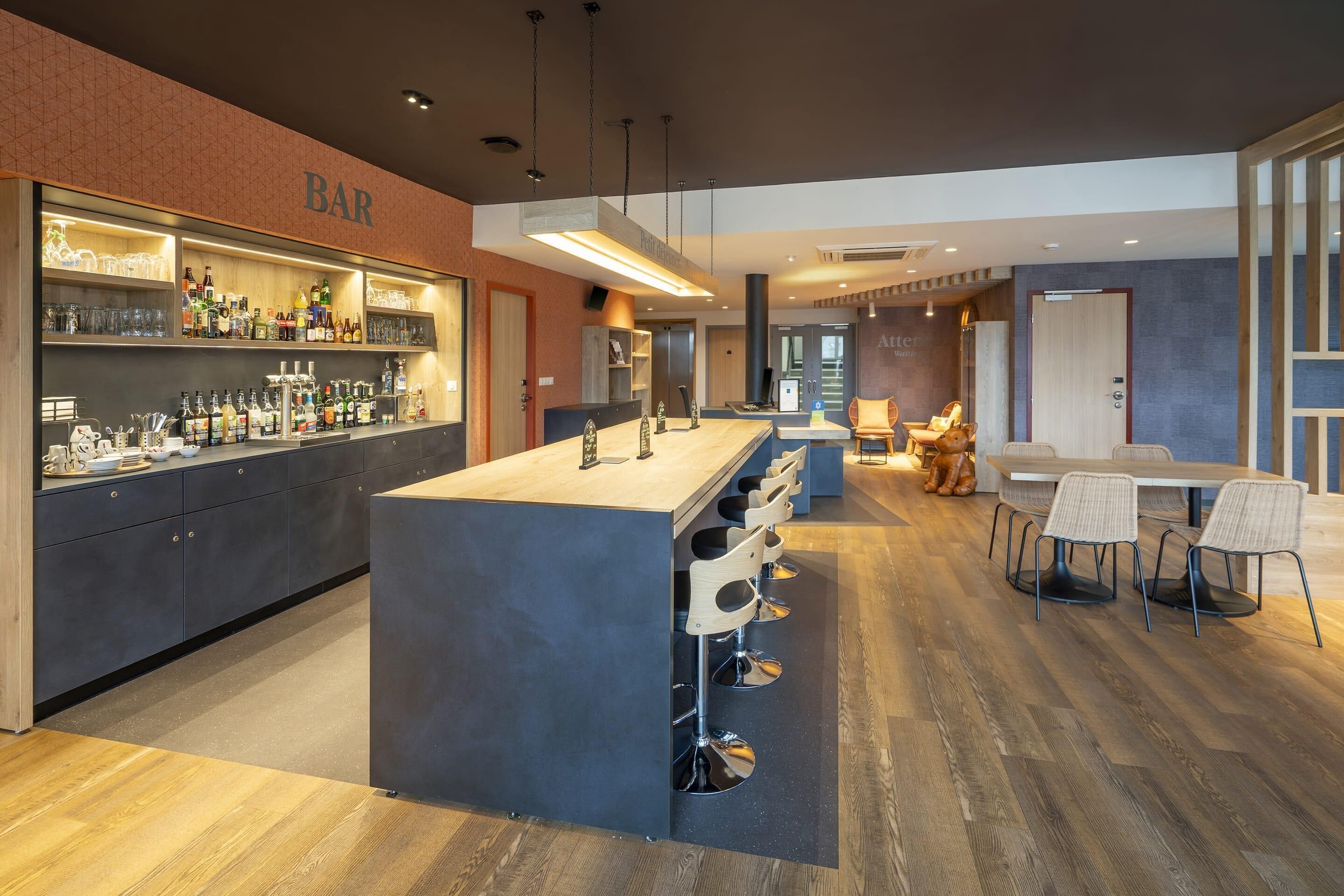 A modern bar area with a central island, bar stools, and a seating area with tables and chairs.