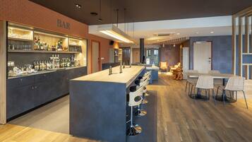 A modern bar area with a central island, bar stools, and a seating area with tables and chairs.