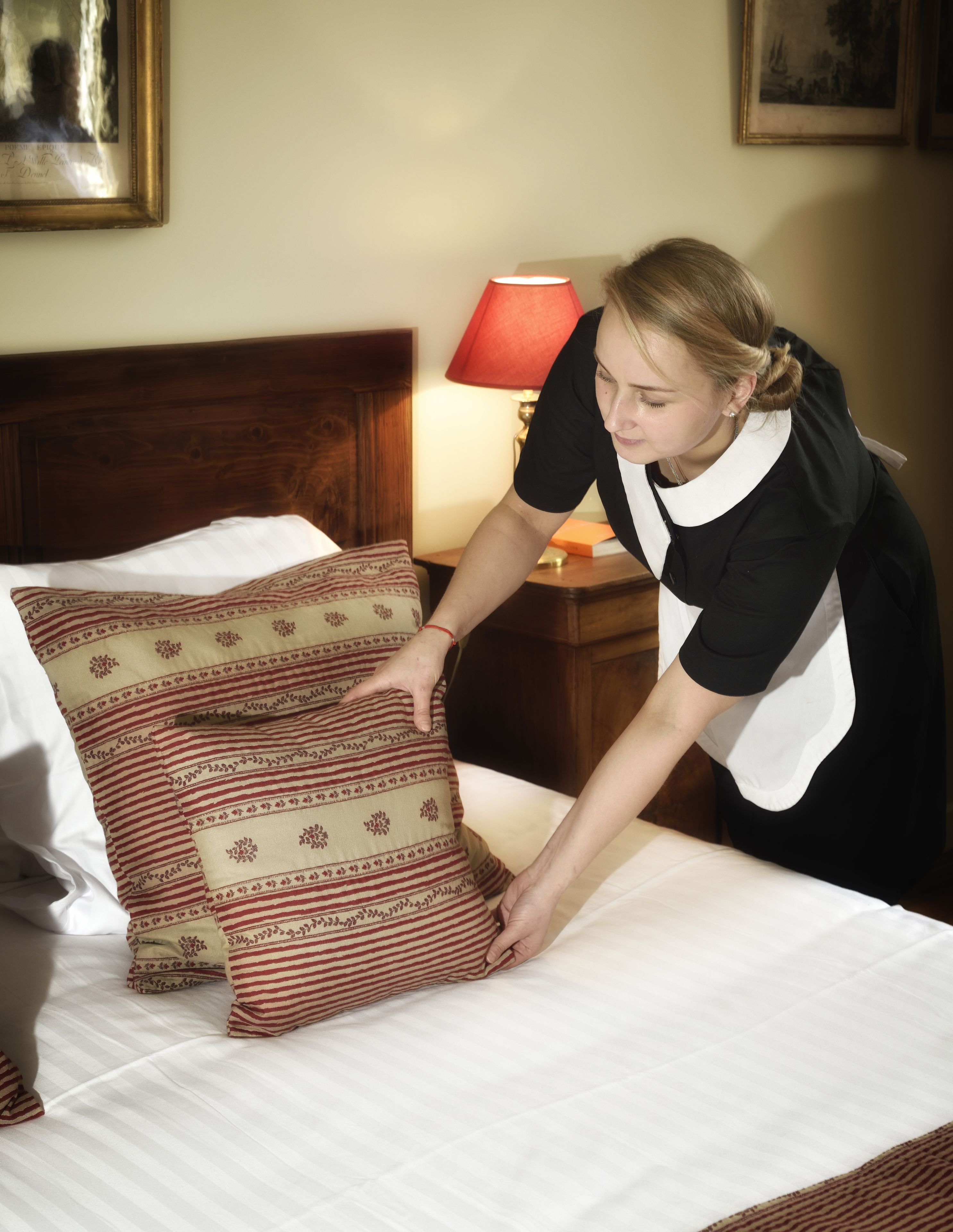 Iemand legt kussens op een bed in een hotelkamer.