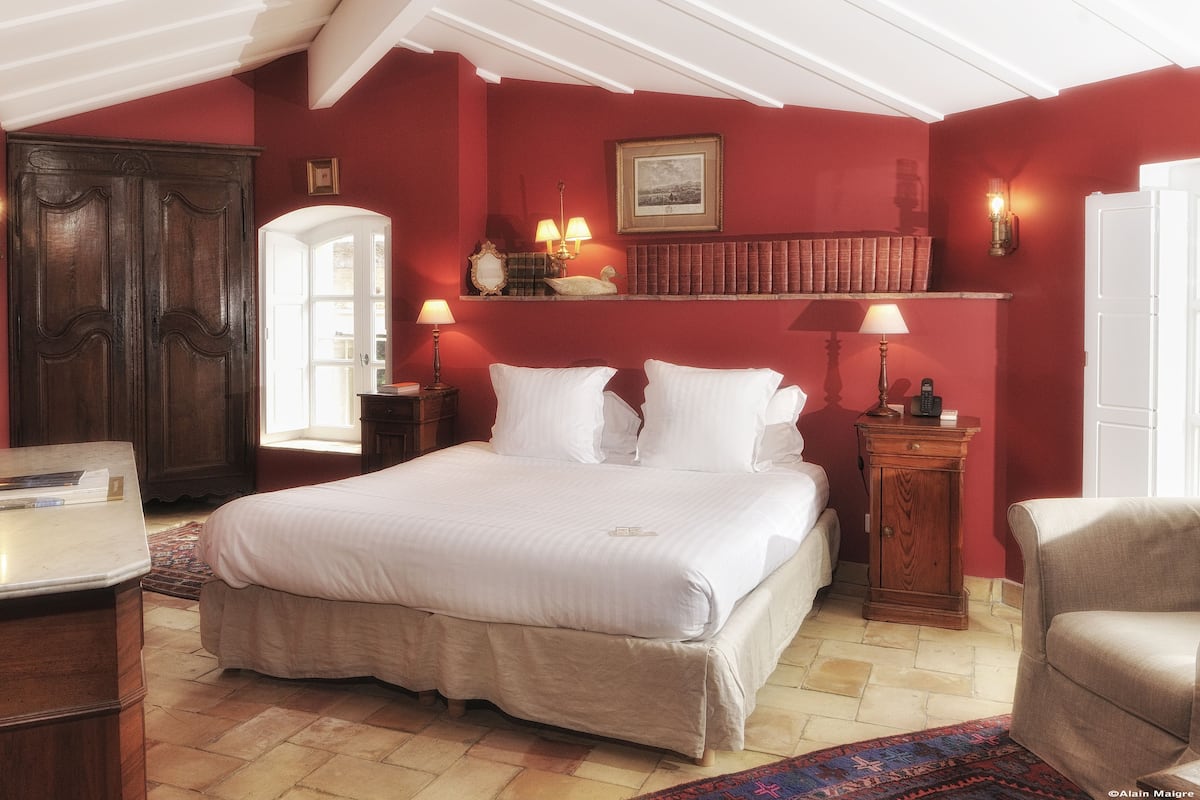 Habitación de hotel con una cama grande, un escritorio, una silla y una estantería.
