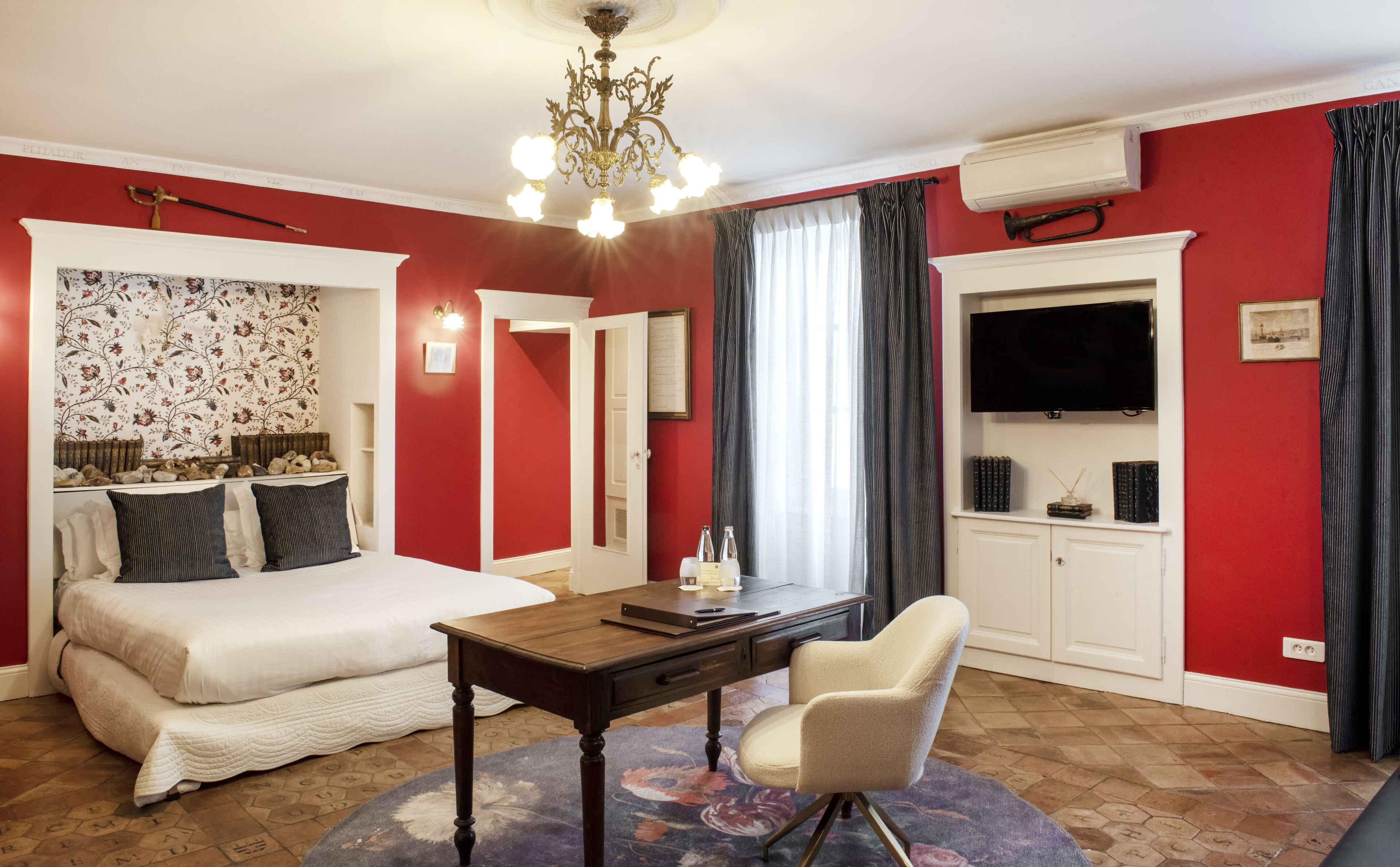 Habitación de hotel con cama, escritorio, silla, televisor y armario.