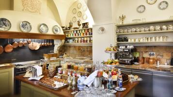 Une cuisine bien équipée, avec des ustensiles de cuisine en cuivre, une variété de bocaux et un assortiment d’assiettes et de tasses rangées sur des étagères.