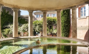 Une cour avec une fontaine, des colonnes et un bâtiment en arrière-plan.