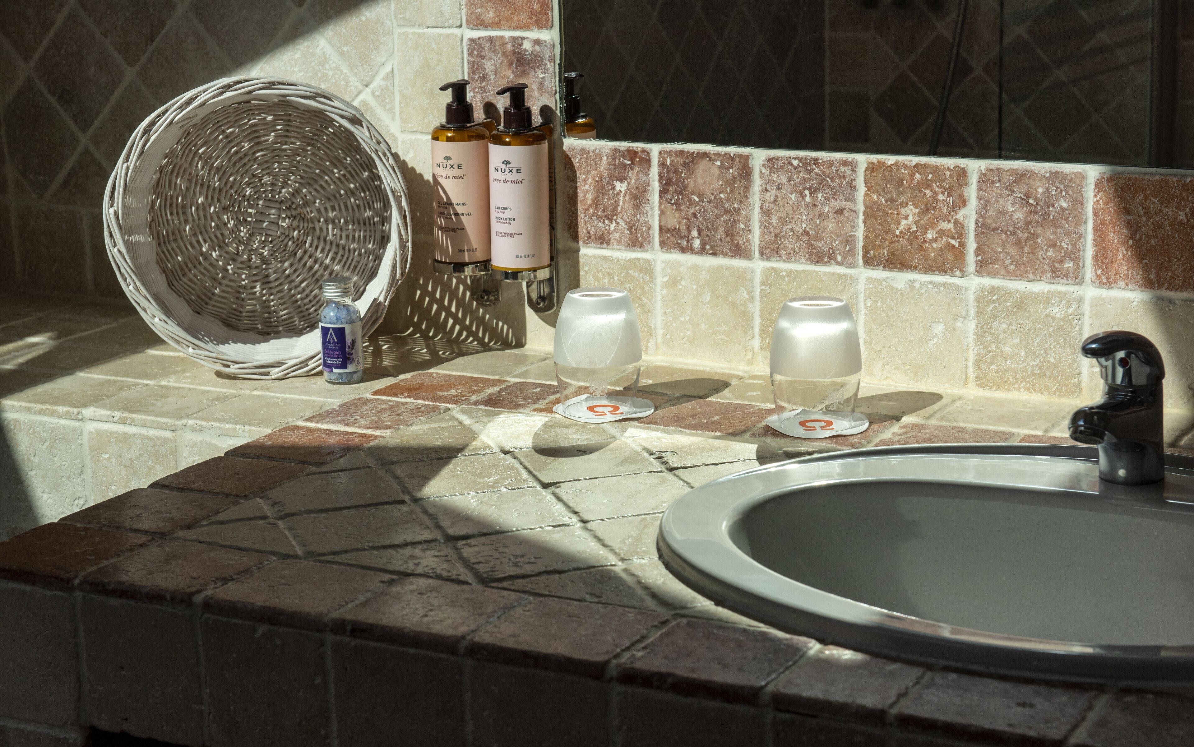 A bathroom with a sink, toiletries, and a woven basket.