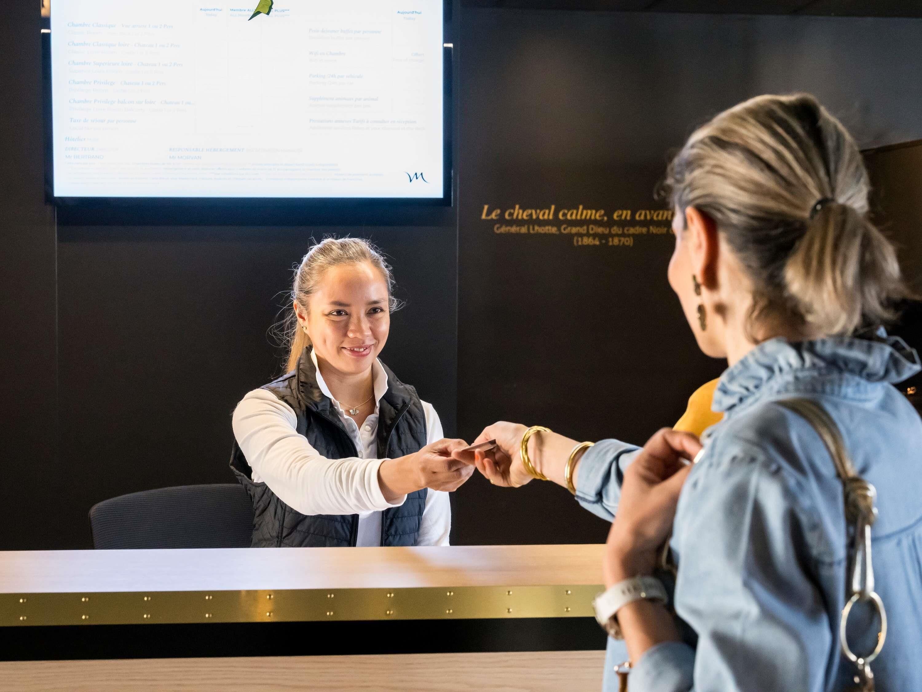 A reception desk with a computer screen displaying a list of rooms and amenities.