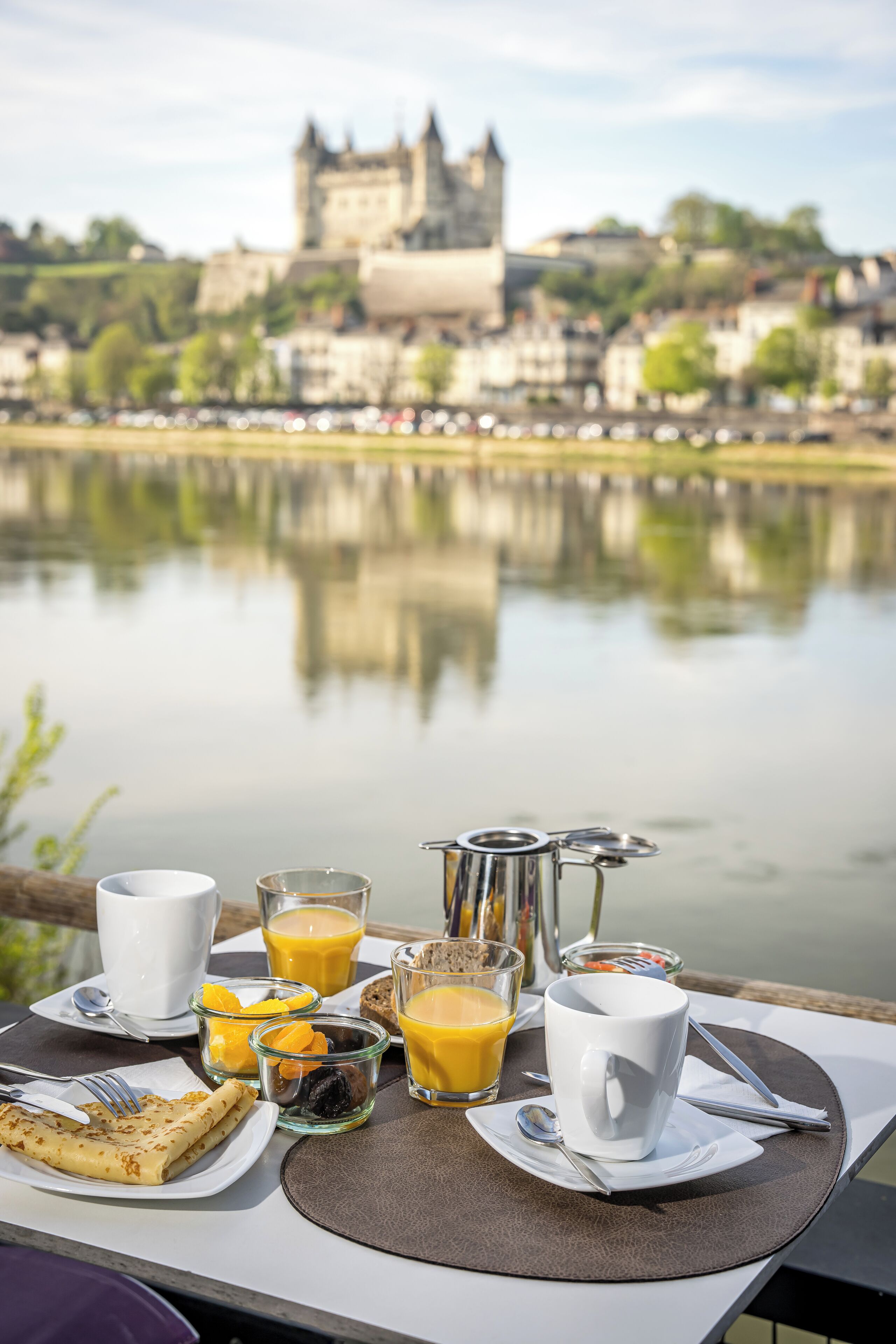 A breakfast table with a view of a castle across a lake.