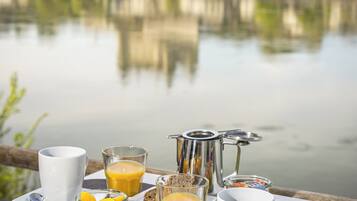 A breakfast table with a view of a castle across a lake.