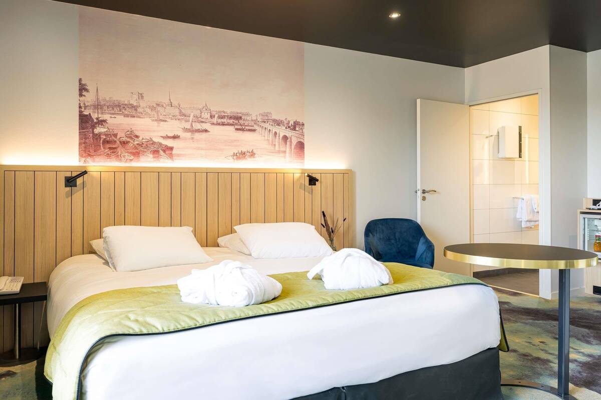 Een hotelkamer met een groot bed, een ronde tafel en een kunstwerk aan de muur.