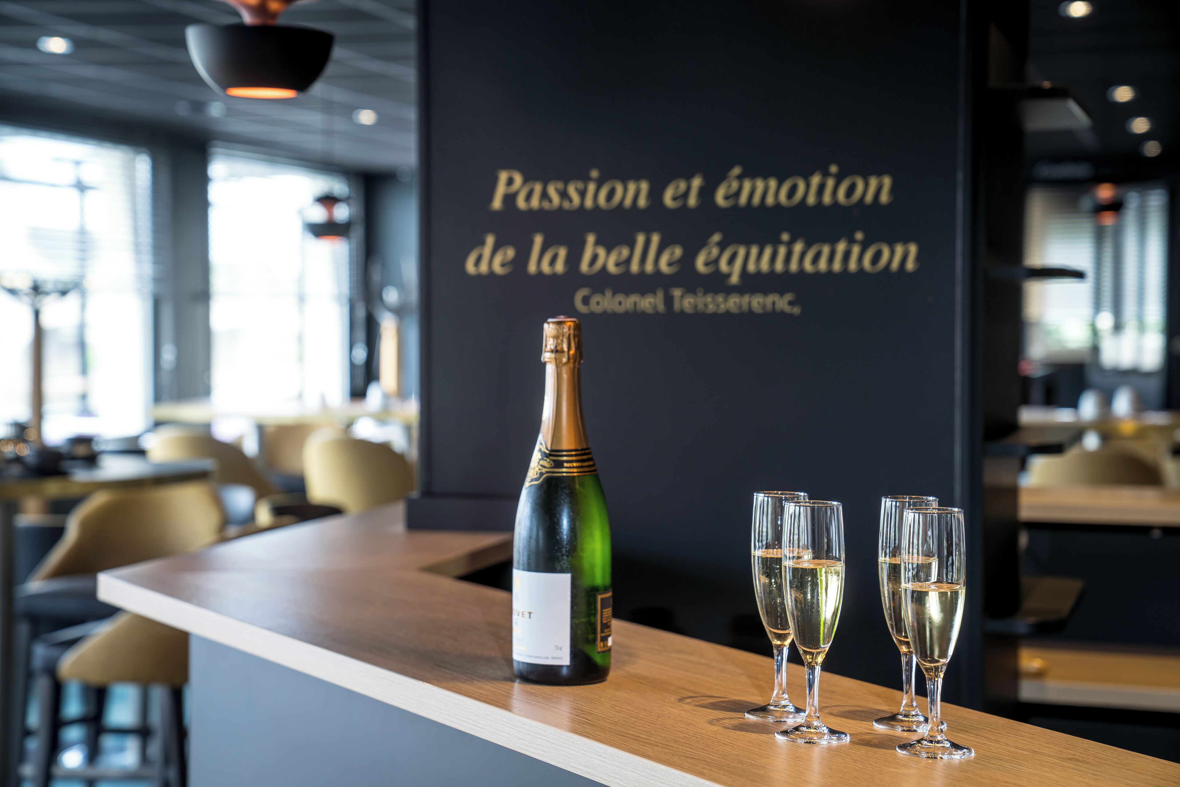 Un coin bar avec une bouteille de champagne et trois verres posés sur un comptoir en bois.