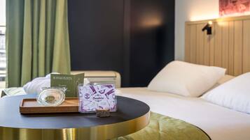 A hotel room with a bed, a round table with a tray, a glass, a box, and a card.