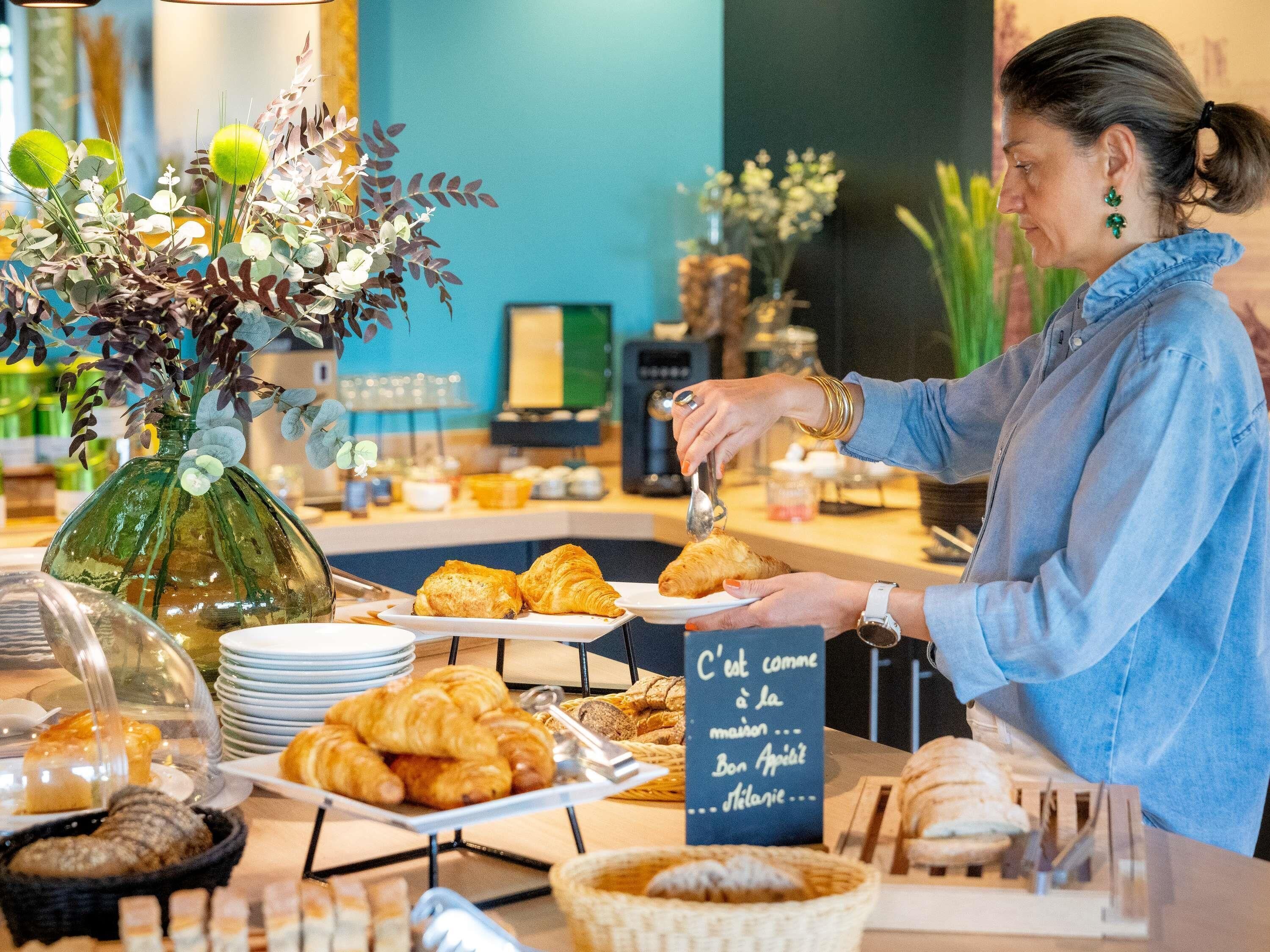 A breakfast buffet with pastries, a vase of flowers, and a sign in French.