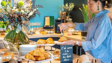 A breakfast buffet with pastries, a vase of flowers, and a sign in French.